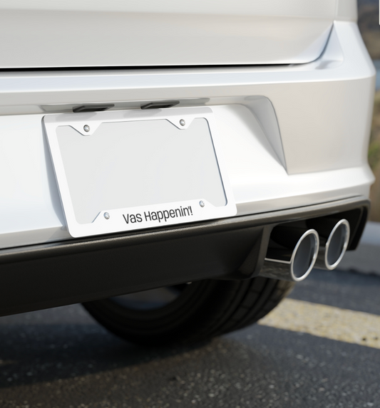 Silver One Direction inspired license plate frame installed on the back of a car with the Zayn Malik quote “Vas Happenin’!” printed along the bottom.